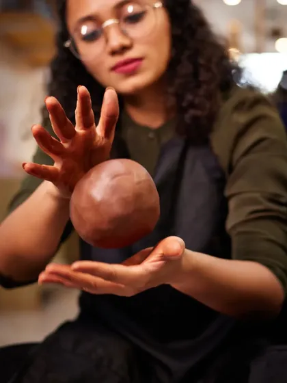 Unleashing creative power. Our instructor playfully channels her energy into a ball of clay, reminding us that art is a powerful force for expression and transformation.