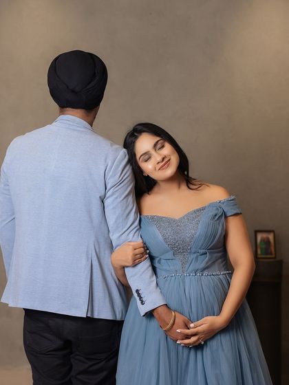 A portrait of love and support. The mother-to-be rests her head on her partner's shoulder, a gesture of trust and comfort, beautifully captured in their elegant attire.