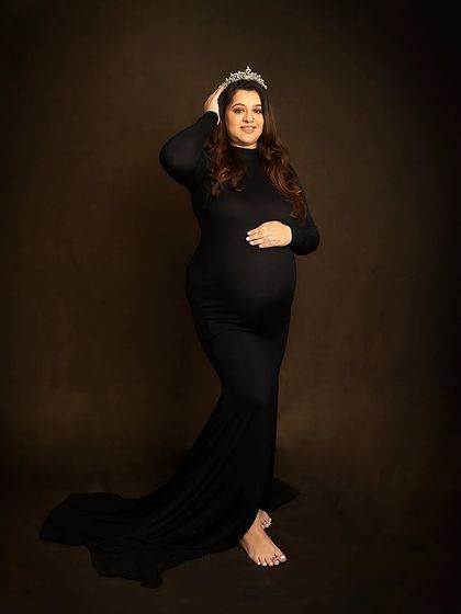 Every mother is a queen. A simple tiara adds a touch of royalty to this elegant portrait in a classic black maternity gown.