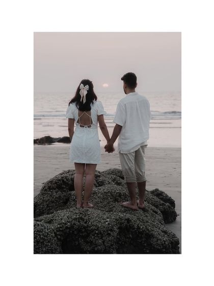 A beautiful shot from behind, showing the couple holding hands and watching the sunset. The bow in her hair adds a sweet, romantic detail.
