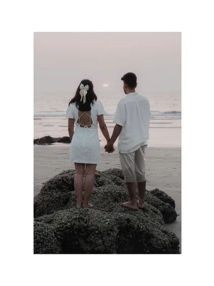 A beautiful shot from behind, showing the couple holding hands and watching the sunset. The bow in her hair adds a sweet, romantic detail.