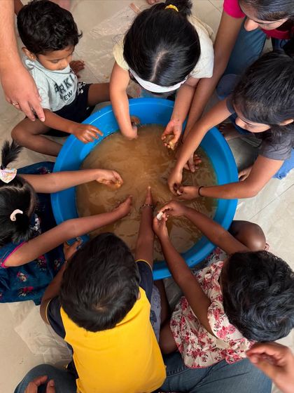 A top-down view of teamwork and discovery. In our mud play sessions, children gather around to feel the texture of the earth, working together and sharing the sensory experience. It is a fantastic group activity that encourages social interaction and collaborative play.