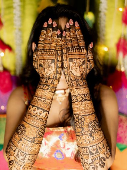 This bride is glowing as she shows off her full bridal mehendi. The design is filled with peacocks and floral patterns, perfect for a grand celebration.