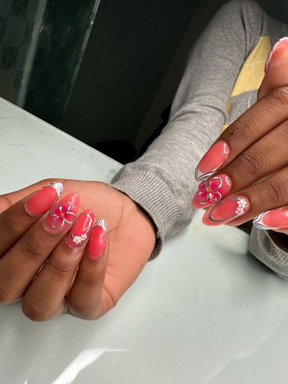 Another angle of this beautiful coral and 3D flower nail set, showing the consistency and detail in the student's work.