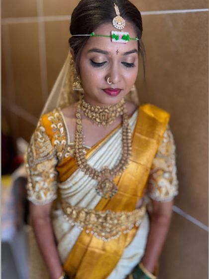 A beautiful Muhurtham look with soft golden eyeshadow and a deep red lip. The focus is on creating a divine, goddess-like appearance that is perfect for the wedding ceremony.