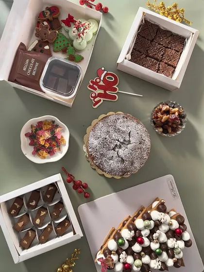 The holiday season is my favorite time to bake. This image displays the wide variety of treats from my Christmas menu, including a Christmas tree cookie cake, classic plum cake, festive fudge, and decorated sugar cookies.