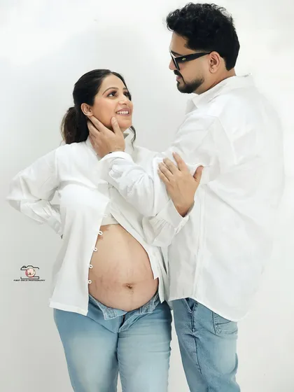 Sometimes the most beautiful moments are the simplest. This casual studio portrait, with the couple in classic jeans and white shirts, brings the focus to the pure joy and connection as they admire the baby bump.