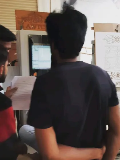 Students review a printout of G-code while programming a job on the CNC machine, learning to bridge the gap between digital design and physical production.