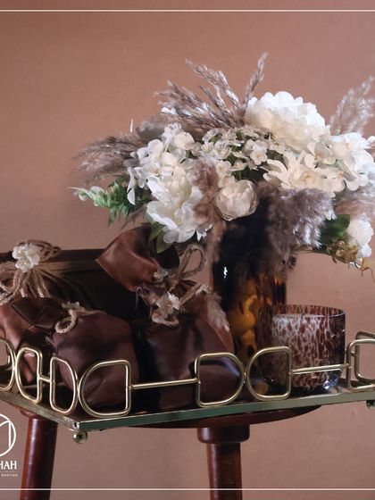 A rustic yet elegant Lohri hamper, featuring a brass-handled tray, scented candle, and leather-like potlis. Perfect for celebrating a little one's first Lohri.