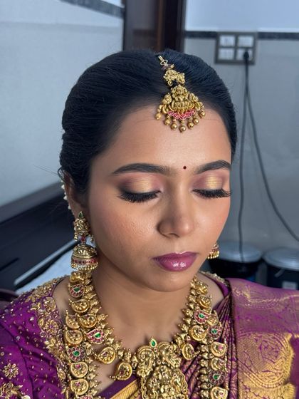 A detailed close-up of Anitha's eye makeup. This shot highlights the shimmering gold and pink tones on her eyelids, which add a touch of glamour to her traditional Muhurtham look.