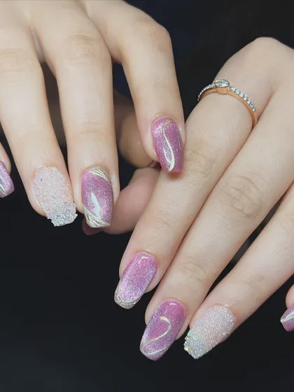 A glamorous set featuring pink cat-eye polish, gold line art, and a textured sugar glitter nail.