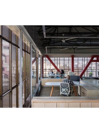 A linear verandah wrapped in an expanded aluminum mesh envelops the 'Hoverspace' office. This feature acts as a climatic buffer, a breakout space, and a semi-transparent screen that filters sunlight and offers views of the city.