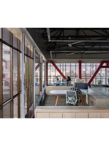 The open-plan office inside "Hoverspace" benefits from the filtered light and views provided by the peripheral verandah. The structural trusses are painted red, becoming sculptural elements within the workspace.