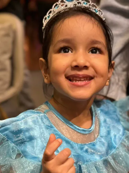 A beautiful little Elsa smiling brightly. Princess dress-up is a wonderful part of the fun here.