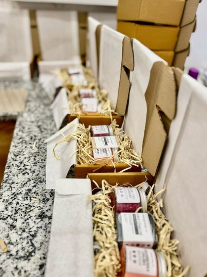 We line our gift boxes with tissue paper and use shredded kraft paper for a rustic, protective, and sustainable presentation. Here you can see hampers being prepared before the products are placed inside.