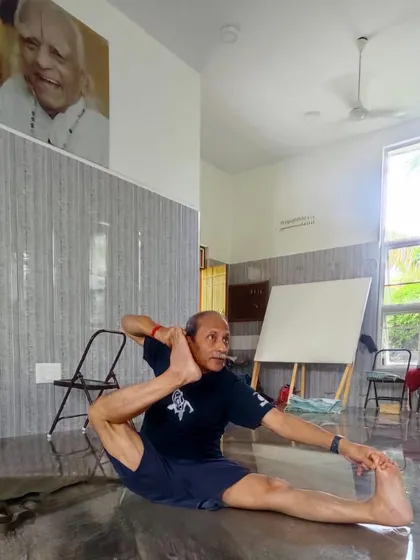 Practicing a variation of Eka Pada Sirsasana under the watchful eye of Guruji. This pose requires significant hip flexibility and core strength, developed through consistent and mindful practice.