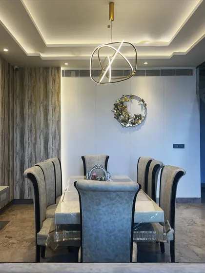 This perspective shows the full dining arrangement, including the high-back upholstered chairs that provide a sense of formality. The tray ceiling with cove lighting adds to the room's height and elegance.