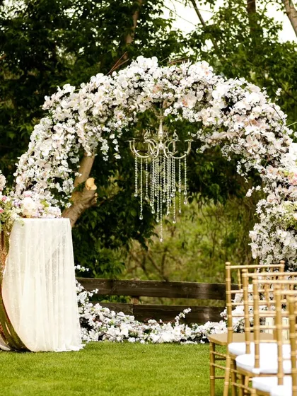 For this outdoor garden wedding, we created a lush floral arch using a cascade of white flowers. A crystal chandelier adds a touch of glamour, perfectly blending natural beauty with elegant design for a magical "I do" moment.