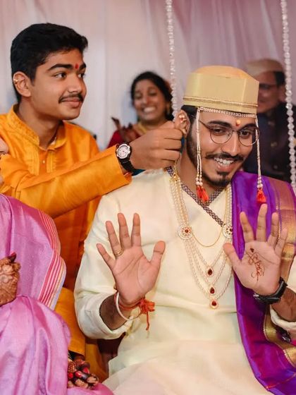 A fun, candid moment during the wedding rituals, with a younger family member playfully interacting with the groom.