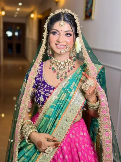 A vibrant and colorful bridal look. The combination of a purple blouse and a turquoise and pink lehenga is complemented by a fresh and glowing makeup look.