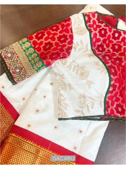 An amalgamation of colors, textures, and embroideries. This blouse combines red Benaras fabric with white embroidered panels and a heavily detailed sleeve cuff.