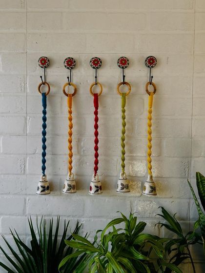 Our miniature macrame set of bells is now live. This image shows a set of five, with colorful knotted cords and hand-painted ceramic bells, complete with matching hooks for easy installation.