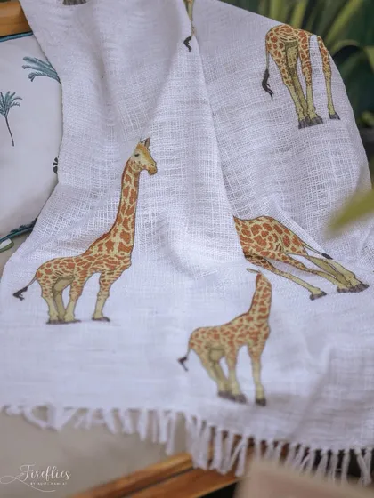 A custom-printed throw blanket with a giraffe pattern, draped over a sofa to add another layer of thematic detail and comfort.