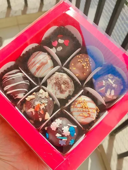 A box of nine of my assorted, handmade chocolate truffles. Each one is uniquely decorated with sprinkles, nuts, or chocolate drizzles. This is a budget-friendly yet decadent gift option.