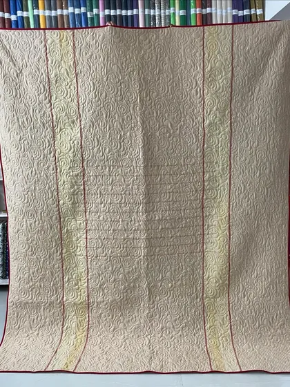The back of a reversible memory quilt made from a mother's sarees, featuring a lovely cream color.