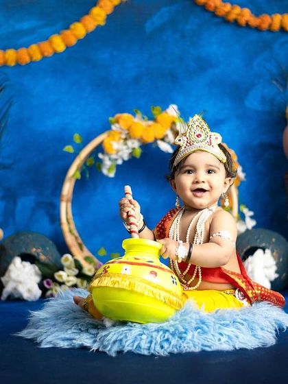 A wide shot of our beautiful Little Krishna setup, featuring a blue backdrop, marigold garlands, and traditional pots.