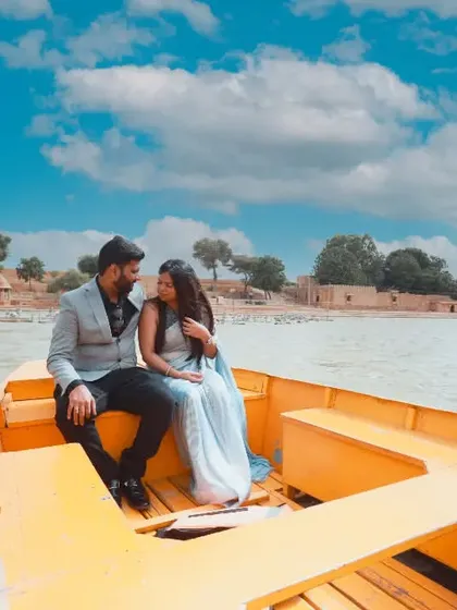 A beautiful shot of a couple on a boat in Gadisar Lake, Jaisalmer, with the historic architecture in the background.