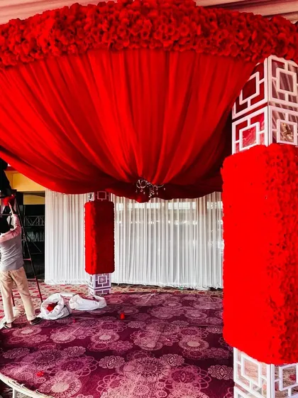A detailed look at the construction of a red floral mandap. The pillars are covered in red flowers, and the top is draped in rich red fabric, showcasing the craftsmanship that goes into my designs.