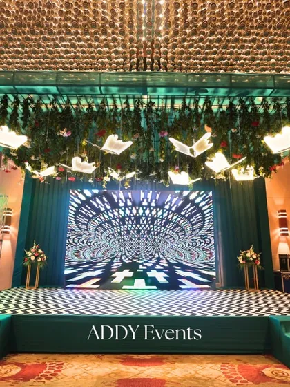 This wide view shows a complete stage setup with a checkered dance floor, an emerald green frame, and a captivating LED backdrop. This design is versatile for corporate Sangeet-style parties, annual celebrations, or themed brand events.