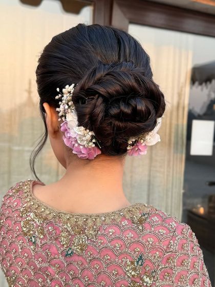 A back view of a soft, romantic updo, with purple and white flowers tucked in for a delicate and pretty finish.