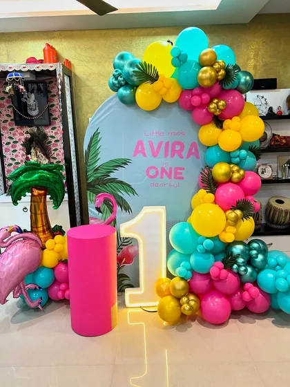 This is a duplicate of ID 41, 103. A vibrant tropical flamingo theme for a first birthday at home. This setup includes a personalized backdrop, a colorful balloon garland, and a flamingo prop.