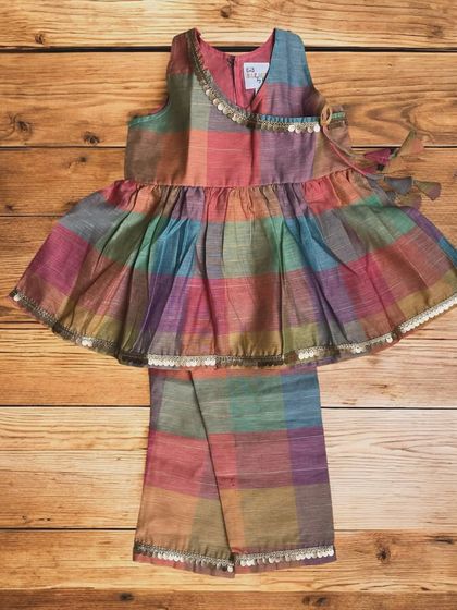 This multicolored plaid peplum top and pants set is made from the softest pure cotton. Adorned with a delicate golden border and playful tassels, it's a dream for both comfort and style.