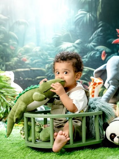 A playful moment in the jungle, as this little explorer chews on a toy crocodile, surrounded by a vibrant, nature-inspired backdrop.