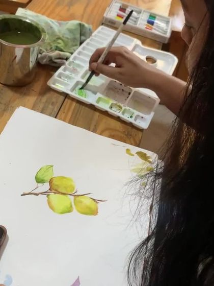 A student works on her lemon painting. Mastering watercolor is a matter of focus, and our classes help you find that creative zone.