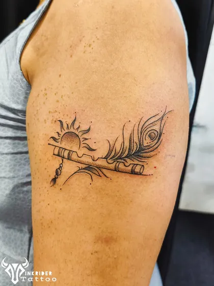 A tribute to Lord Krishna, this tattoo features his flute and a peacock feather against a rising sun. The fine-line work and delicate details bring this divine image to life.