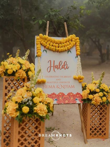 The personalized welcome sign for the Haldi ceremony, adorned with a simple garland of fresh marigolds.