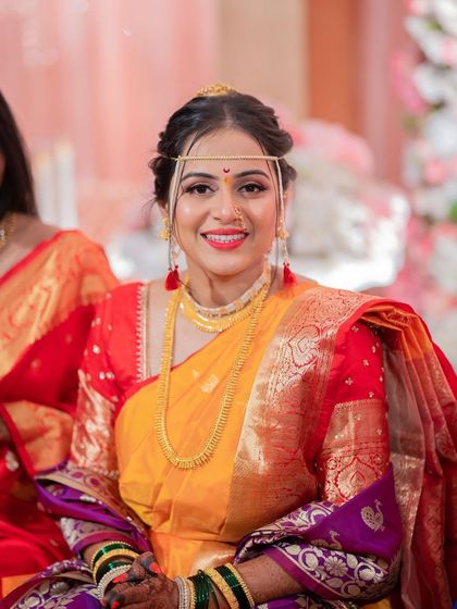 A bright and happy bridal portrait. The makeup is fresh, with a beautiful red lip that complements her traditional attire.