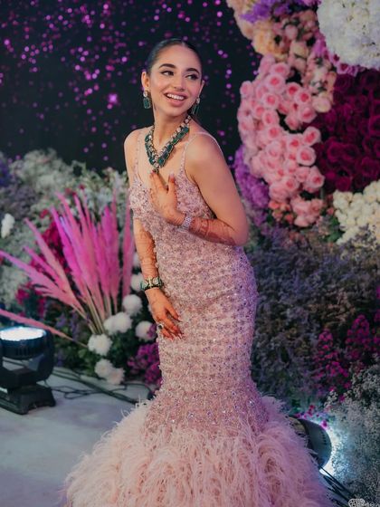 A dreamy reception look. The bride is wearing a stunning pink feathered gown, and her makeup is glamorous yet soft.