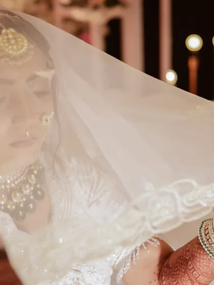 A dreamy, soft-focus shot of the bride through her white veil. This artistic portrait highlights her elegance and the delicate details of her look.