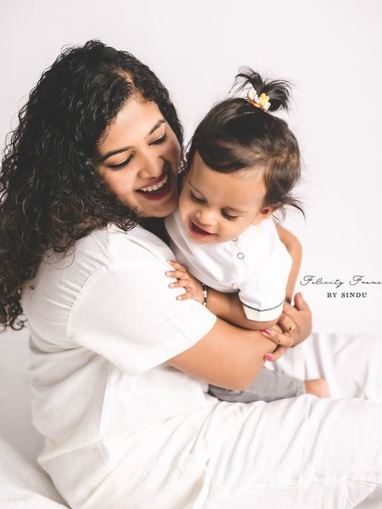 A candid studio shot of a mother and her baby sharing a happy, giggling moment. The clean white background puts all the focus on their pure and simple joy.