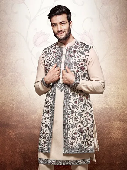 A smiling groom-to-be in our classic beige kurta and embroidered jacket. The floral embroidery adds a touch of celebratory charm to the timeless silhouette.