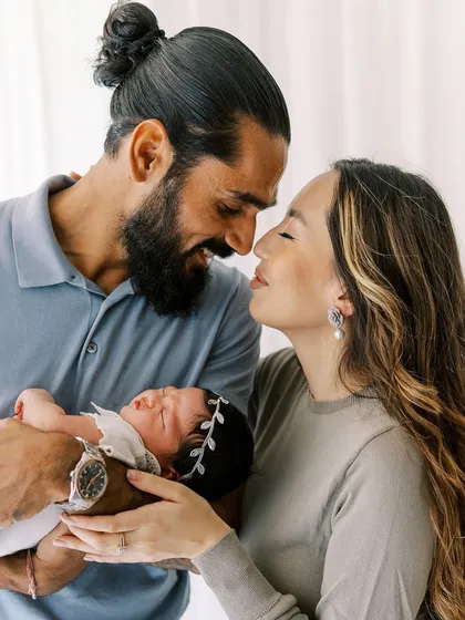 A beautiful portrait of new parents with their sleeping baby girl. The natural light and their loving expressions tell a story of new beginnings.