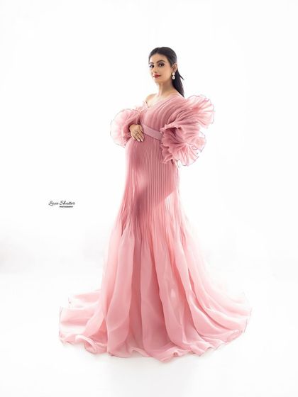 A full-length portrait showcasing the beautiful design and flow of this soft pink pleated gown.
