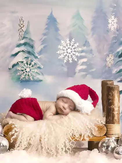 A winter wonderland scene with a baby in a Santa hat sleeping on a log bed.