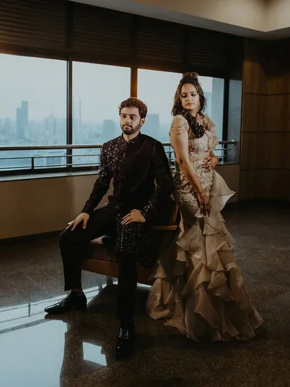 A regal, full-length portrait of the couple against a large window overlooking the city, creating a grand and sophisticated feel.