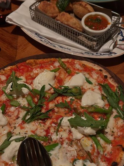 The burrata and asparagus pizza from La Piazza's summer menu. This top down shot highlights the fresh ingredients and beautiful colors of this seasonal special.